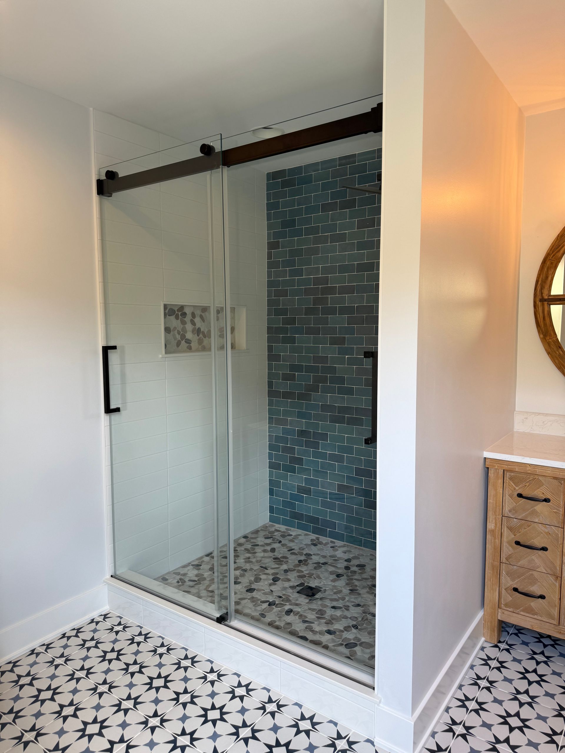 A bathroom with a sliding glass shower door and a mirror.