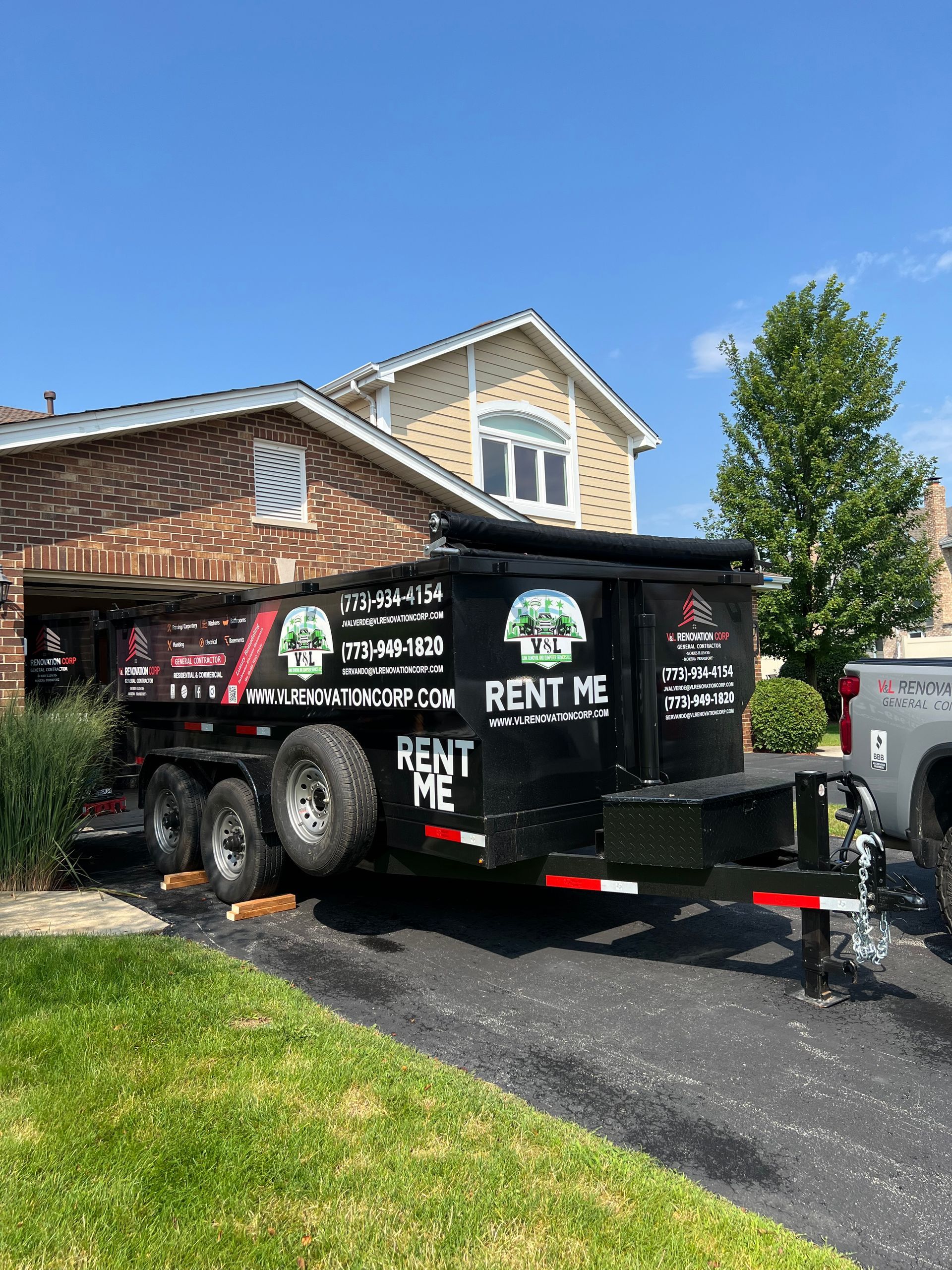 A dumpster trailer is parked in front of a house.