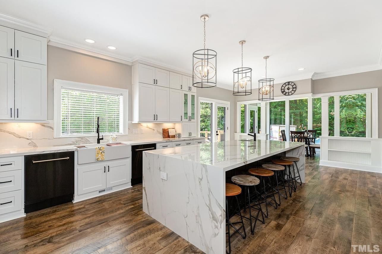 A kitchen with white cabinets , black appliances , and a large island.