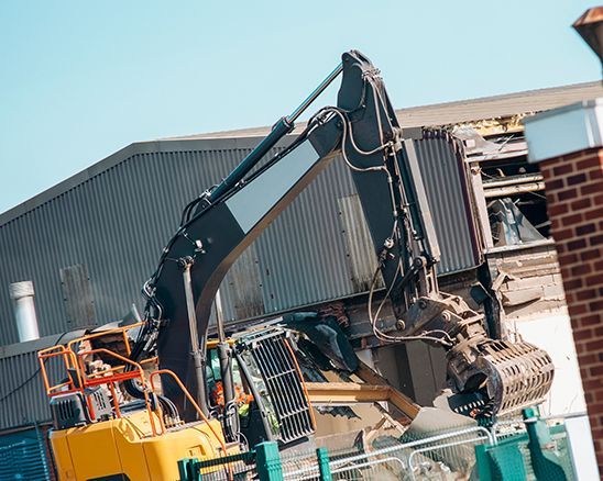 a large excavator is demolishing a building .