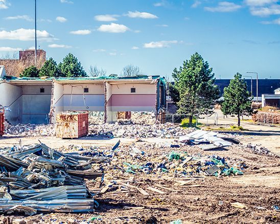 a building is being demolished in a field with a lot of rubble .