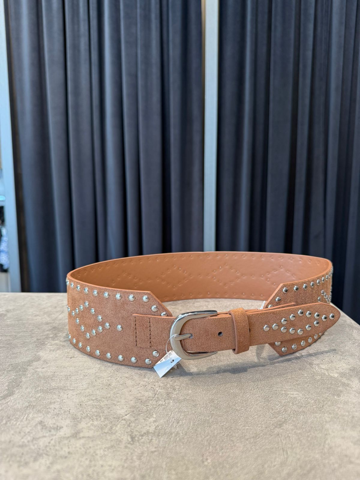 Cinturón ancho de ante marrón con tachuelas y hebilla plateadas.