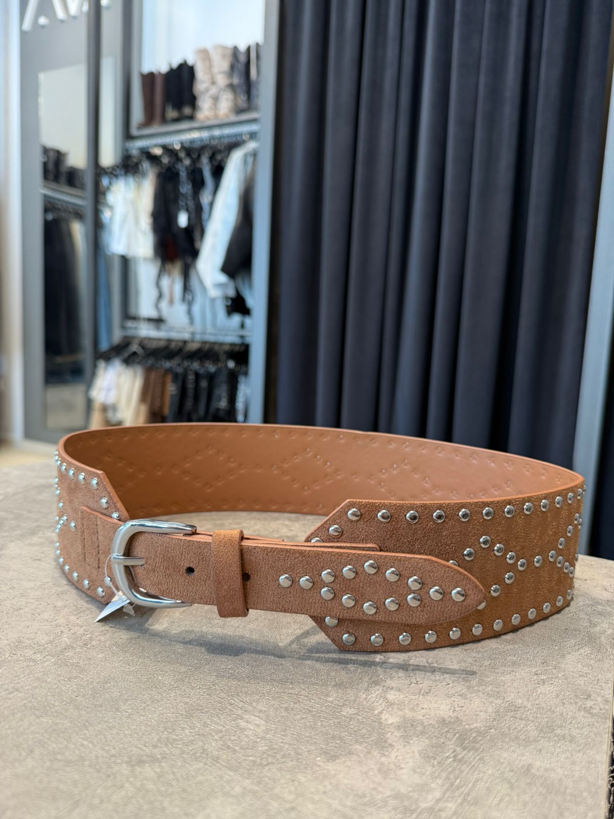 Cinturón ancho de ante marrón con tachuelas y hebilla plateadas.