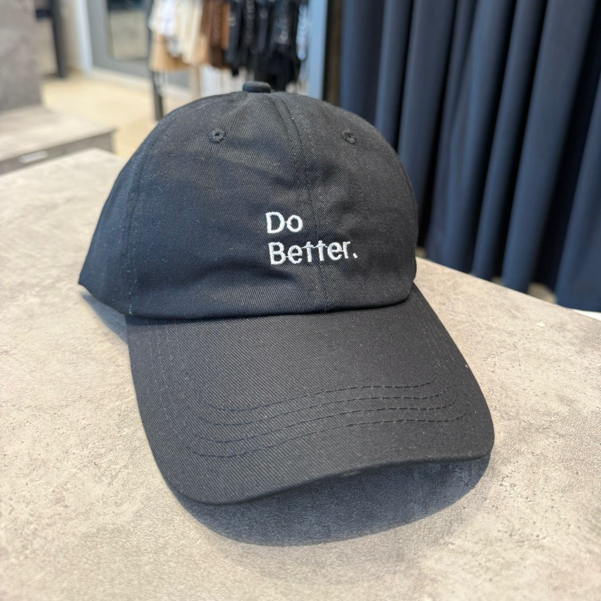 Tres gorras de béisbol apiladas: marrón, canela y negra. La gorra negra tiene bordado 