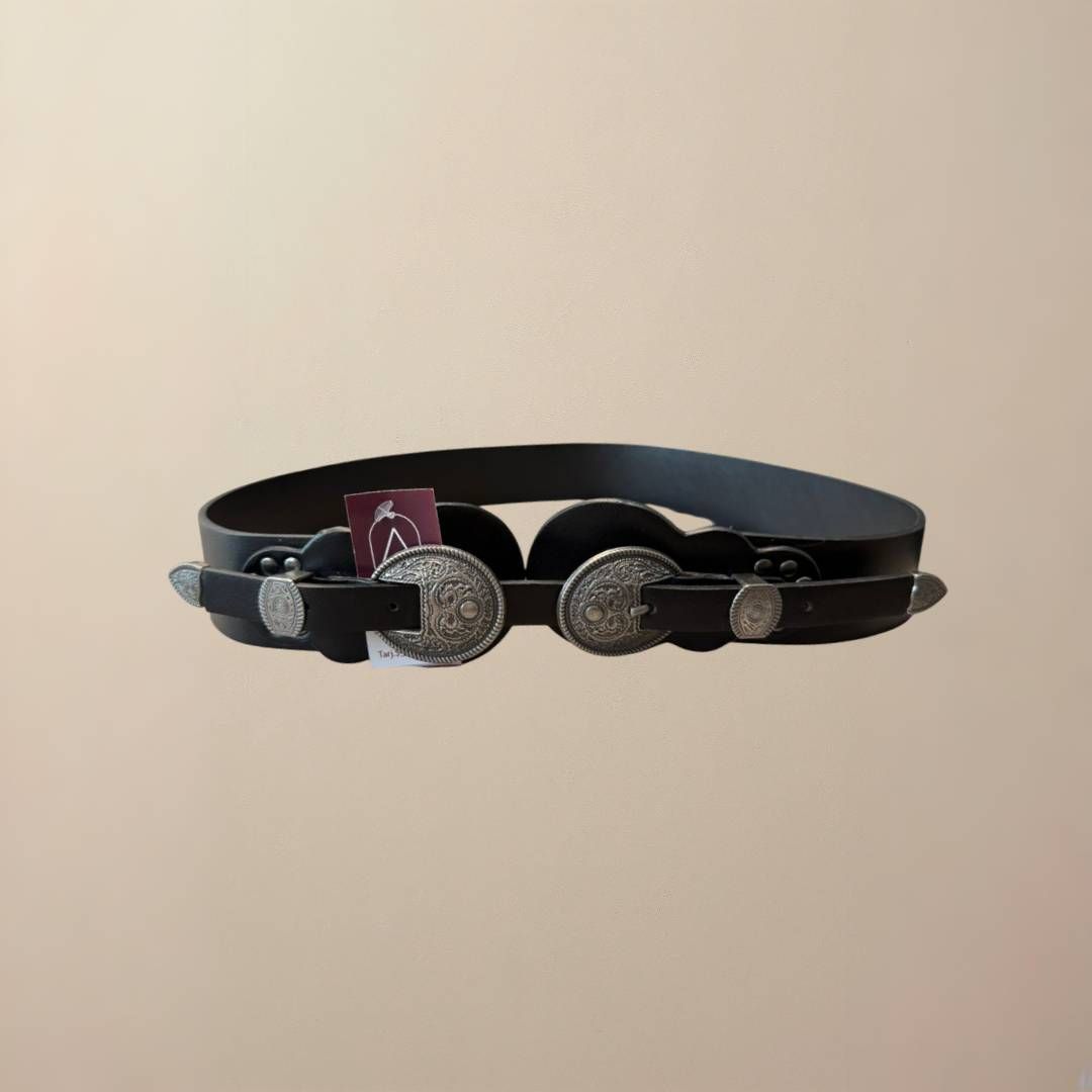 Cinturón de piel negro con herrajes decorativos plateados.