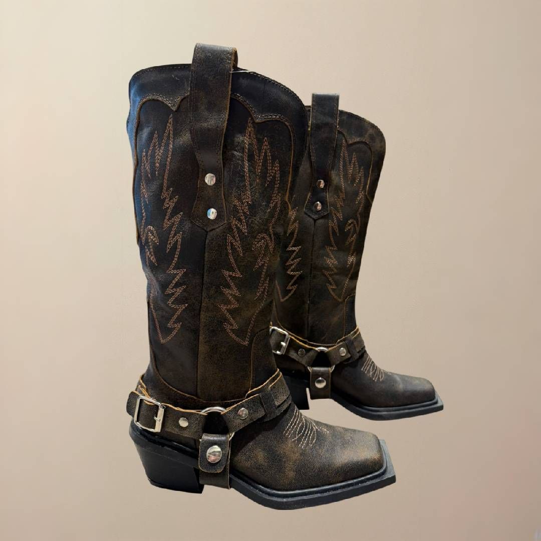 Par de botas vaqueras de piel marrón con costuras decorativas y hebillas.