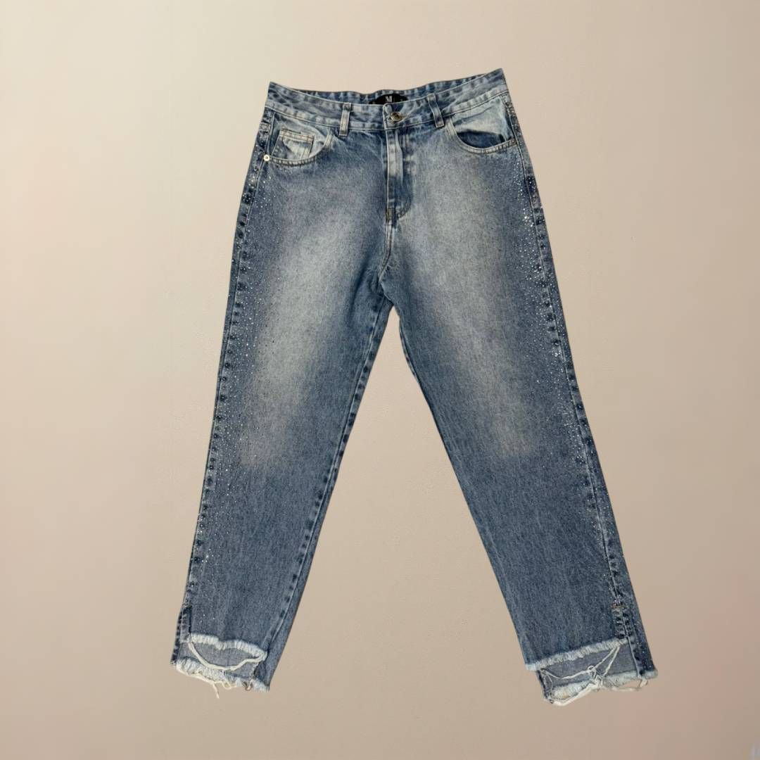 Vaqueros de mezclilla azul descolorido con dobladillo deshilachado sobre fondo neutro.