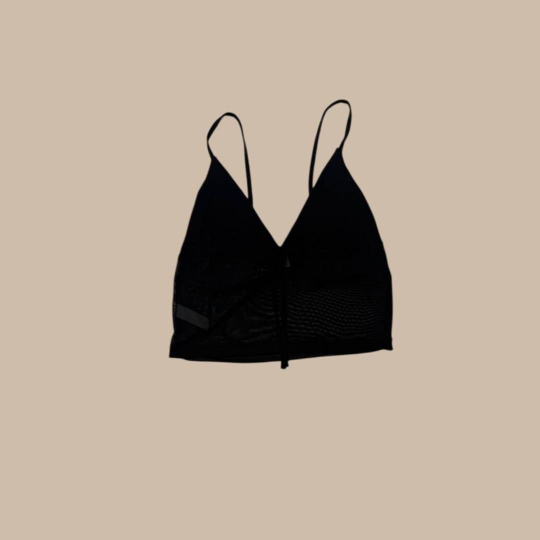 Top corto negro con forma de triángulo y tirantes finos, centrado sobre un fondo neutro.