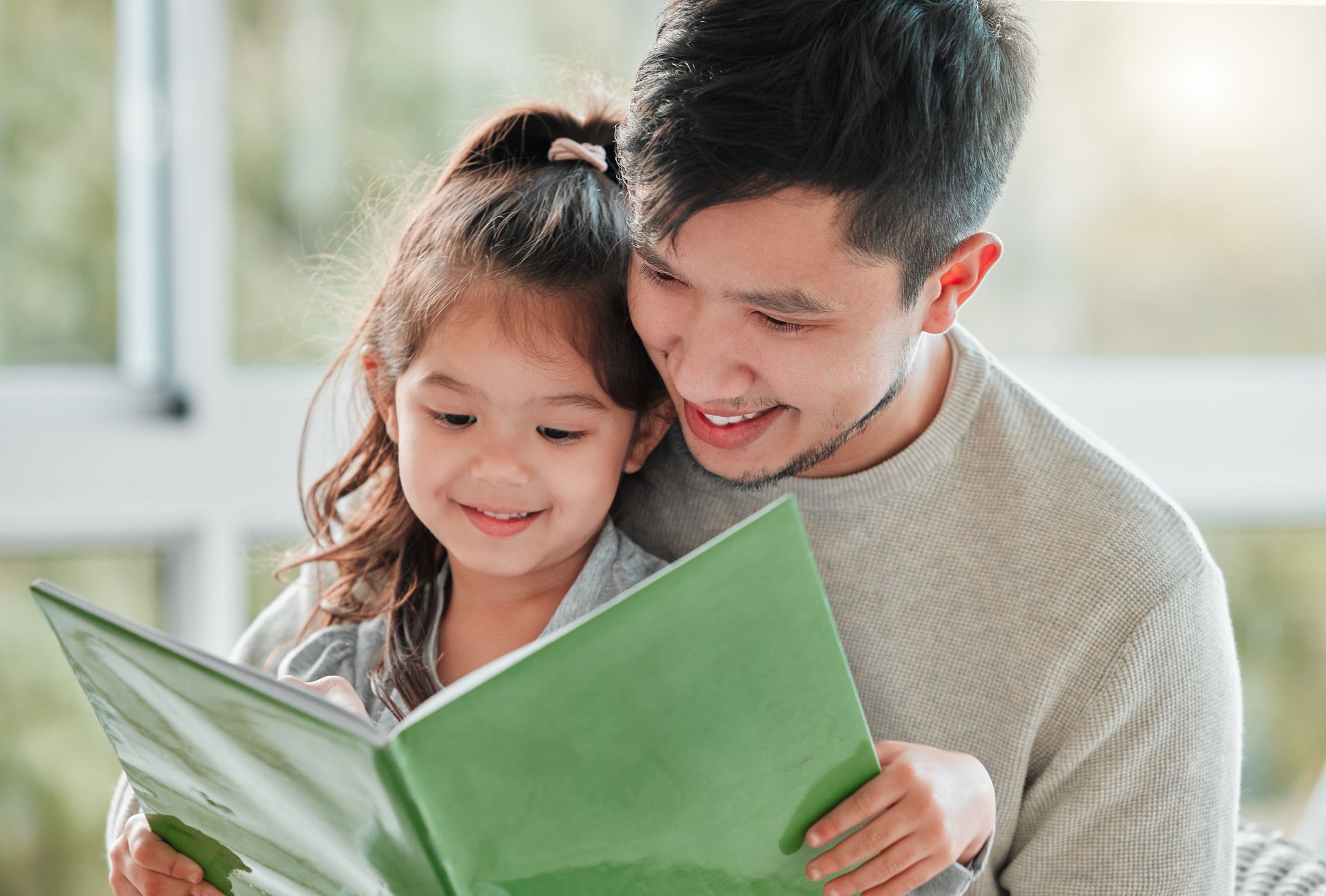 Father and young daughter reading a book.