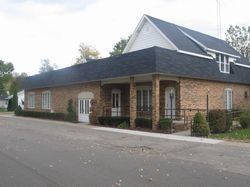 The front door of a house with a porch and plants in front of it.