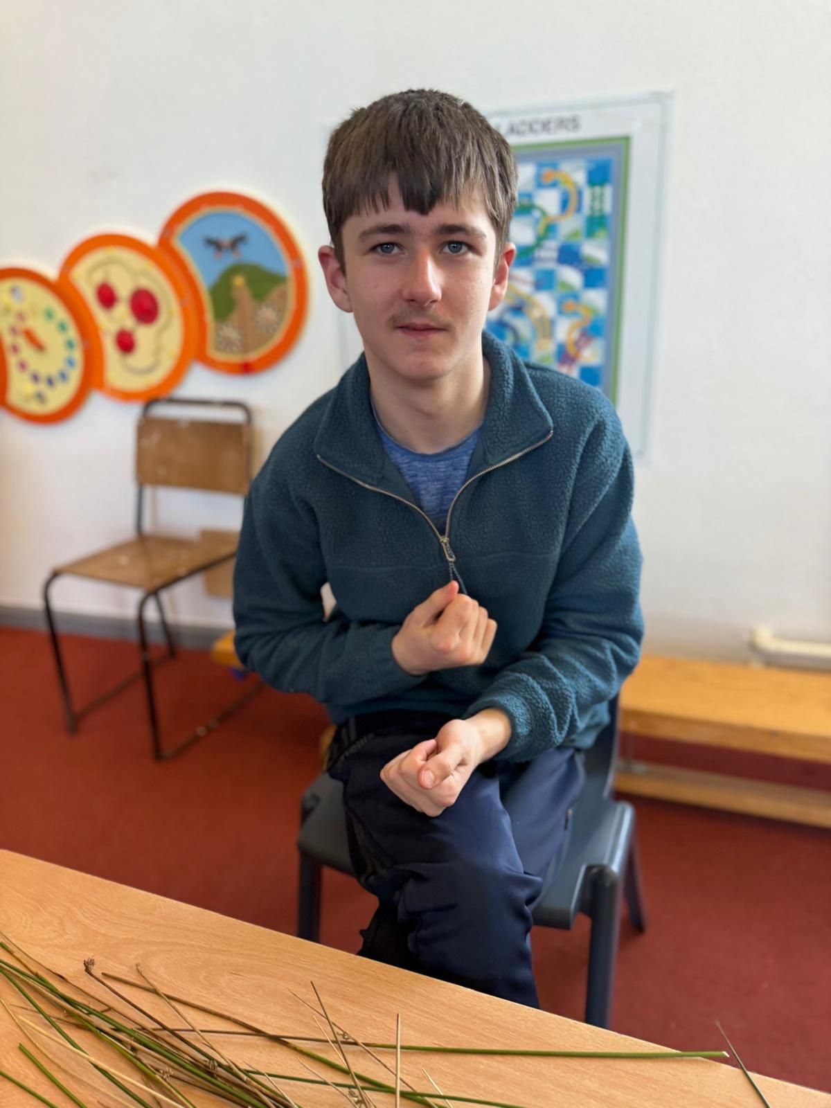 A young man is sitting at a table with a bunch of grass on it