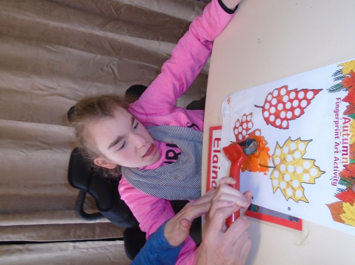 A girl in a pink shirt is sitting at a table