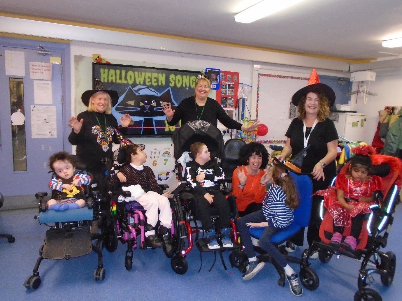 A group of people are posing for a picture in front of a sign that says halloween song