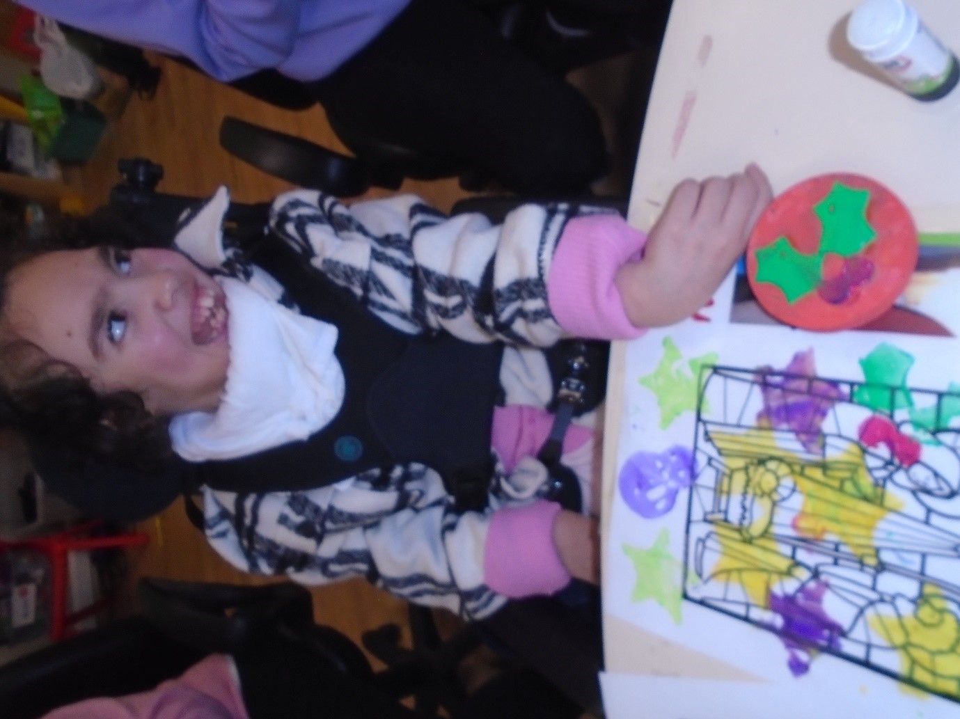 A little girl is sitting at a table with a drawing on it