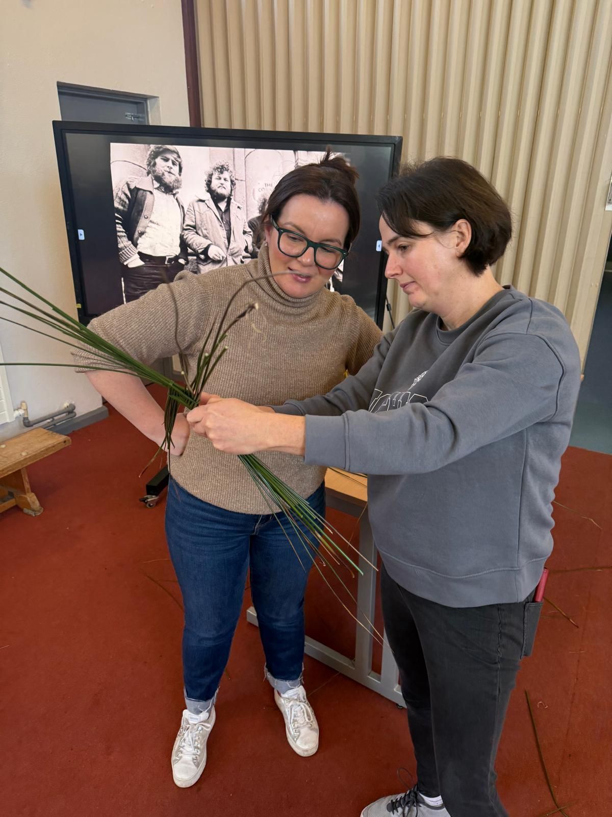 Two women are standing next to each other in front of a television.