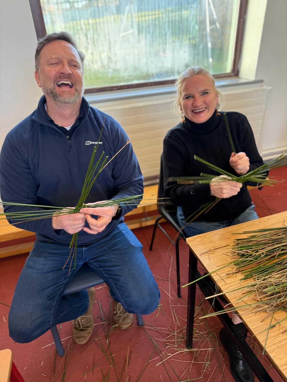A man and a woman are sitting at a table holding sticks.