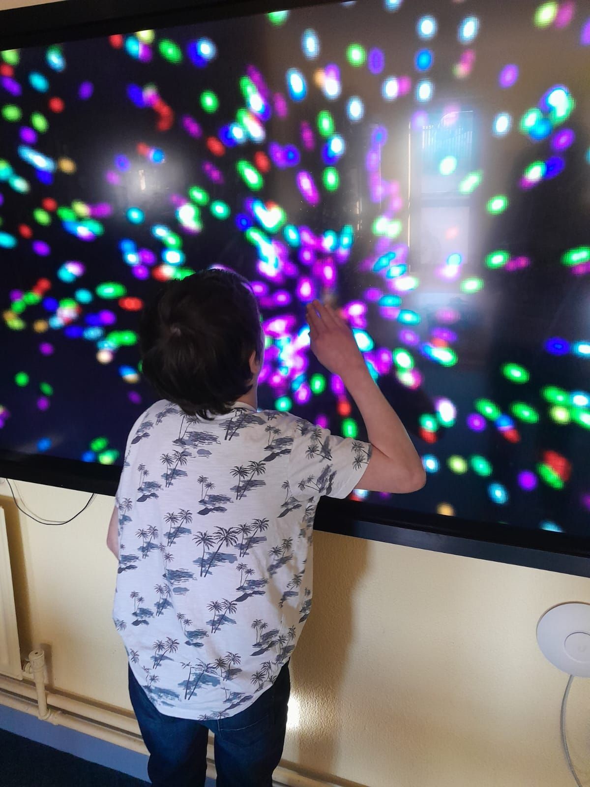 A young boy is playing a game on a large screen