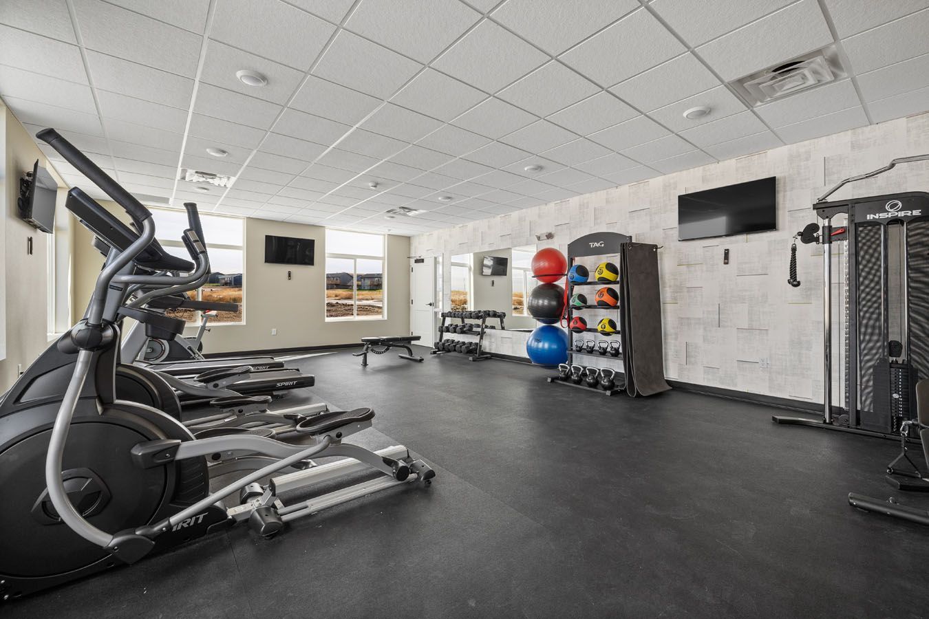 a large gym with a lot of equipment and a lot of windows .