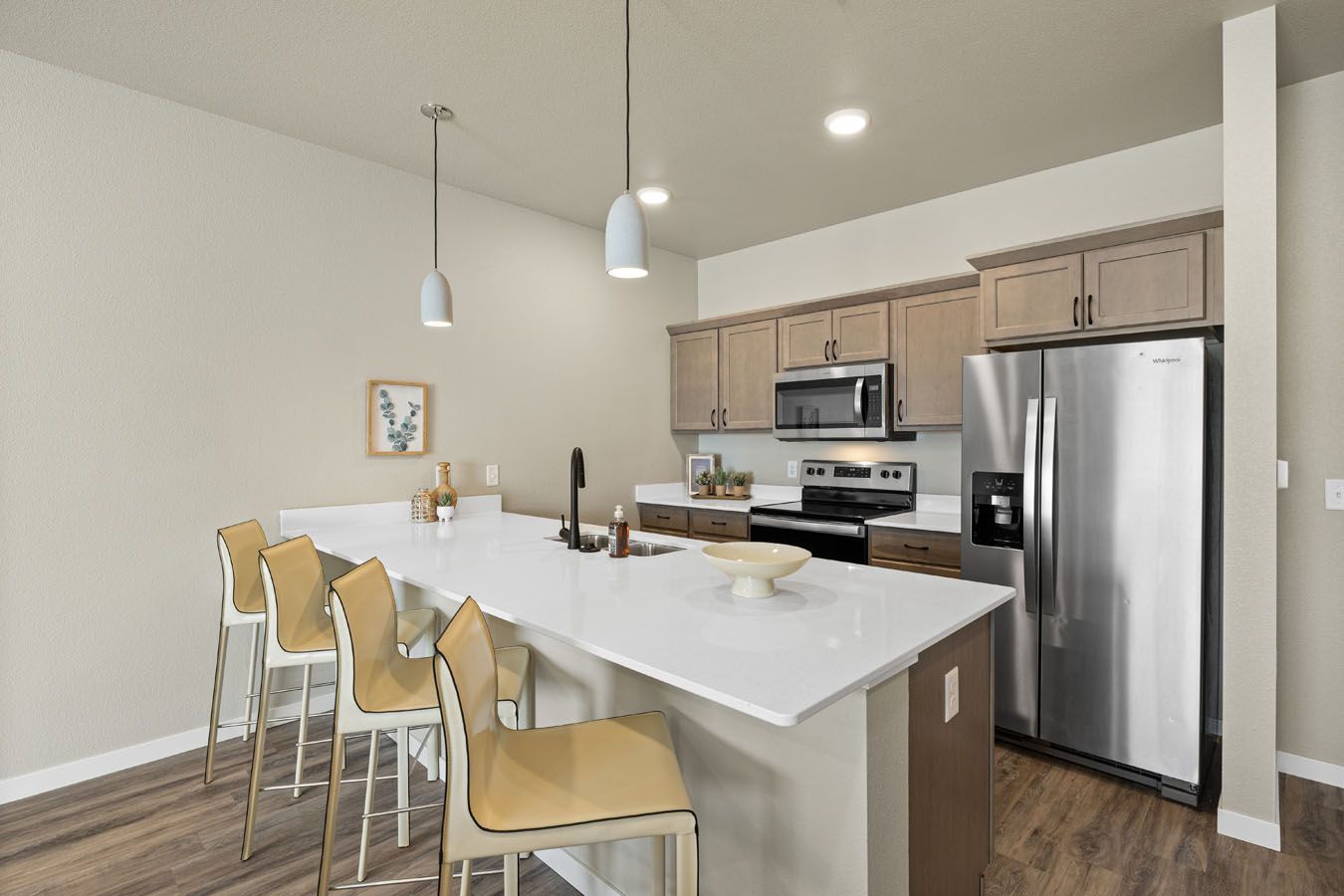 a kitchen with a large island , stainless steel appliances , a refrigerator and a microwave .