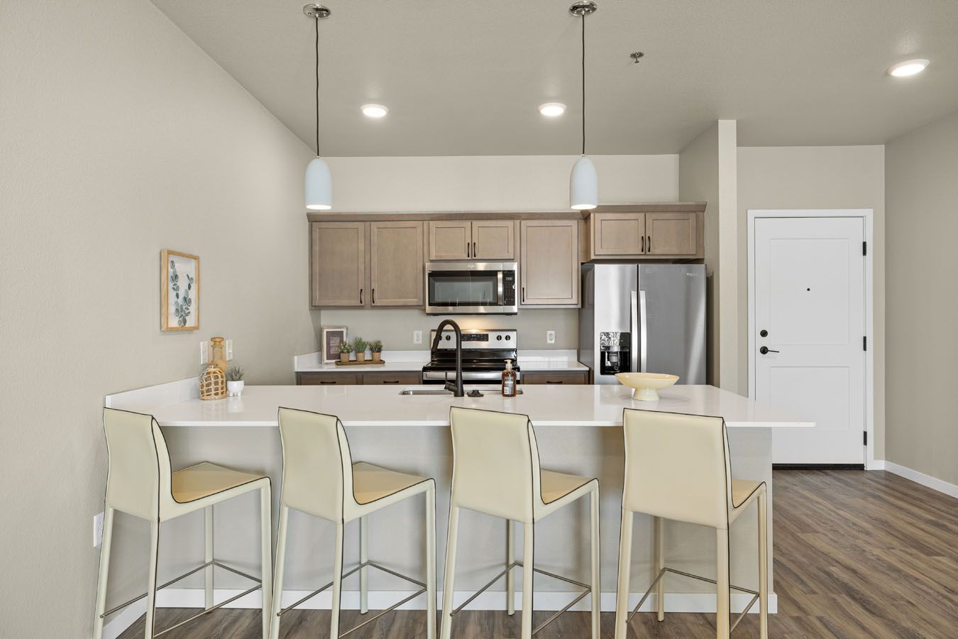 a kitchen with a large island , stools and a refrigerator .