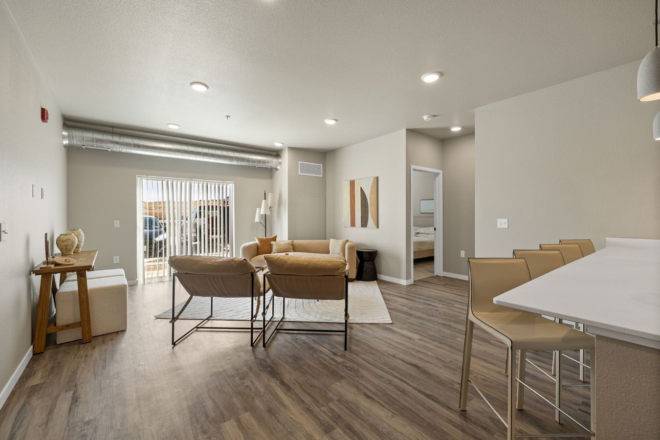 a living room with hardwood floors , a couch , chairs and a table .