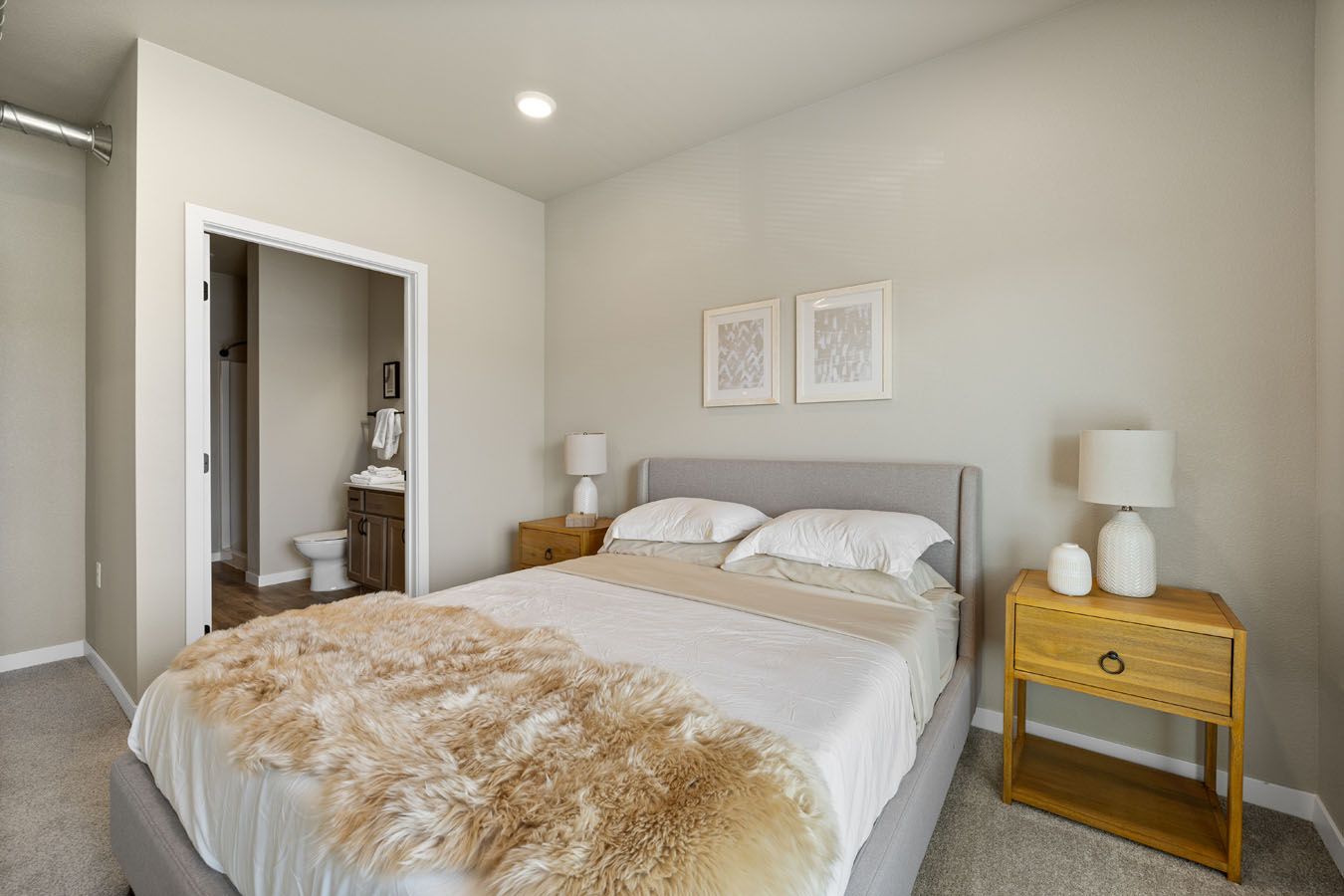 a bedroom with a bed , nightstand , lamps and a bathroom .