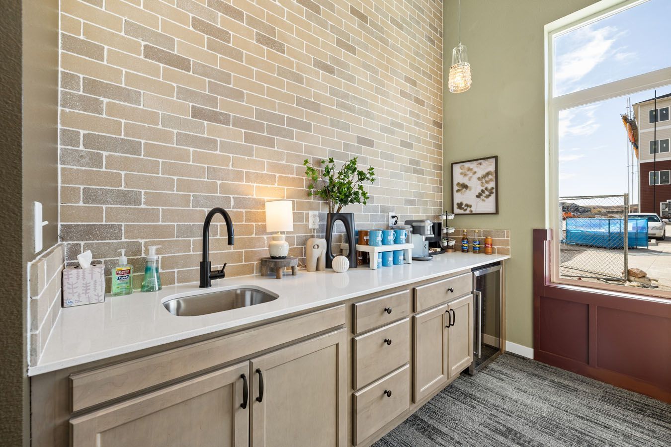 a kitchen with a sink , cabinets , and a brick wall .