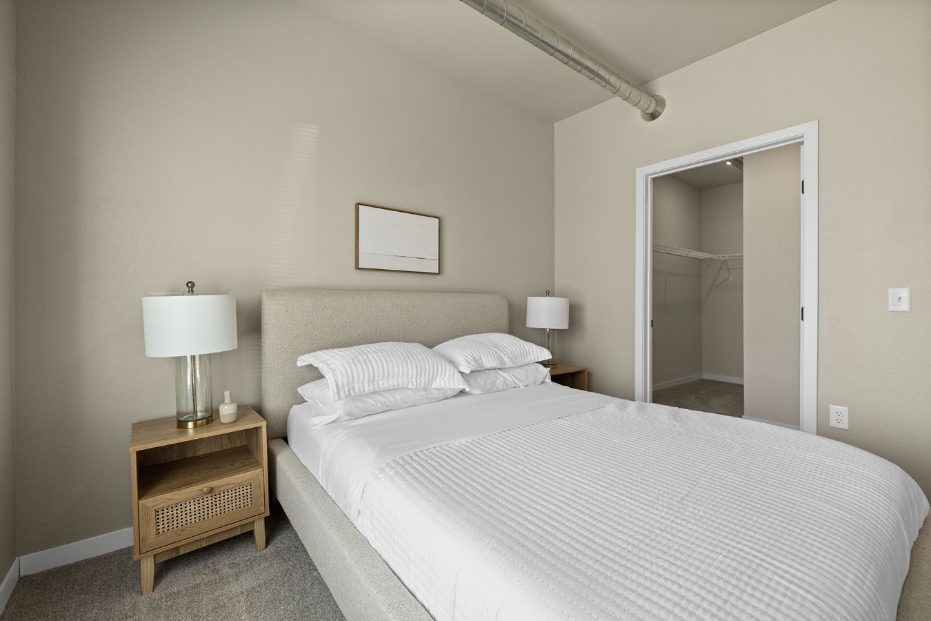 a bedroom with a bed , nightstand , lamps and a walk in closet .