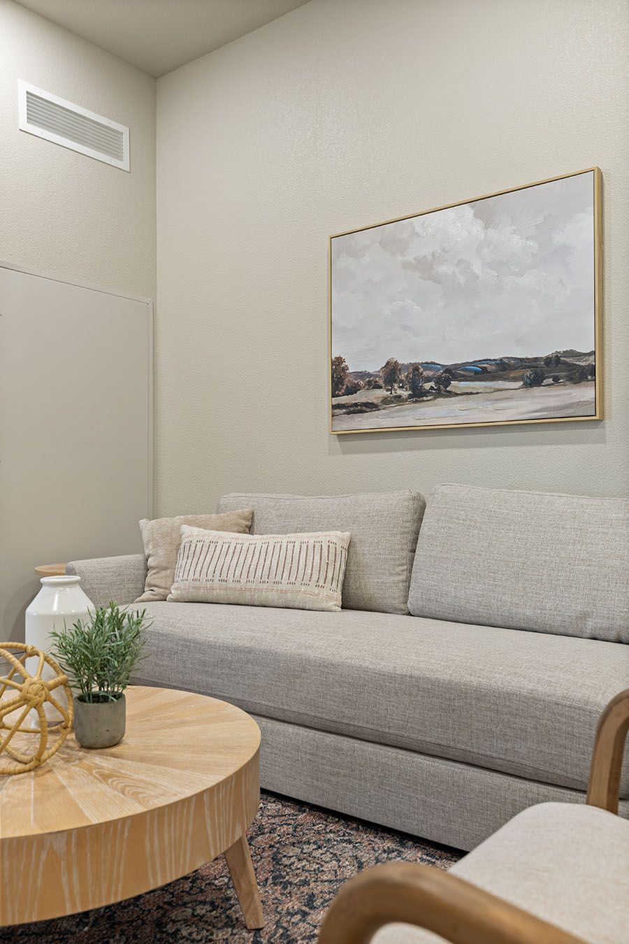 a living room with a couch , table , chair and painting on the wall .