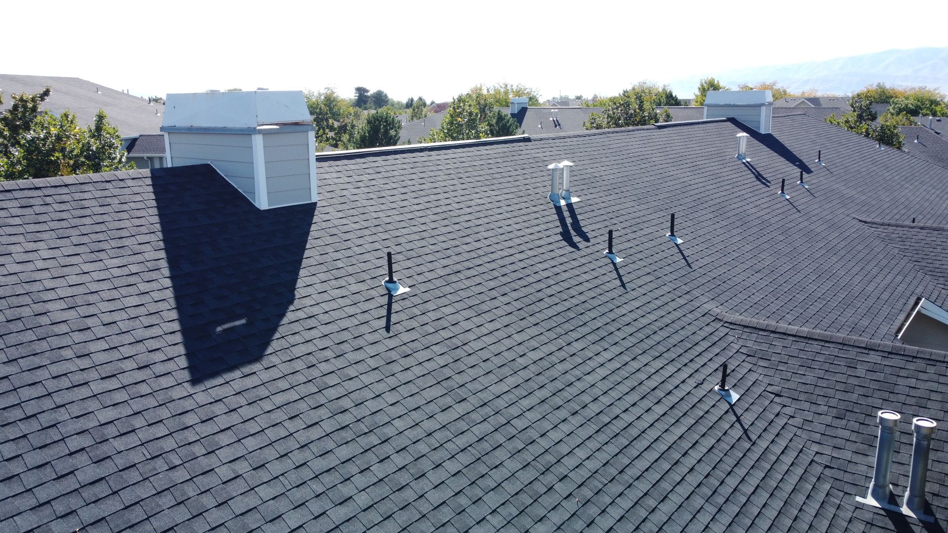 Two workers installing shingles on a roof of a house under construction