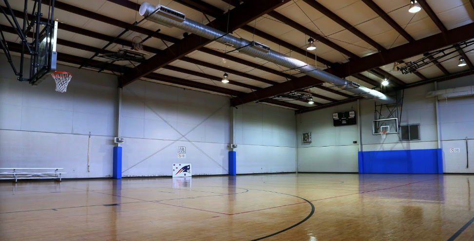 An empty indoor basketball court with a basketball hoop