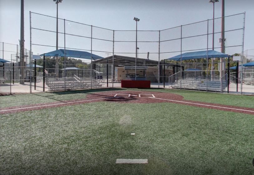 An empty baseball field with a fence and umbrellas