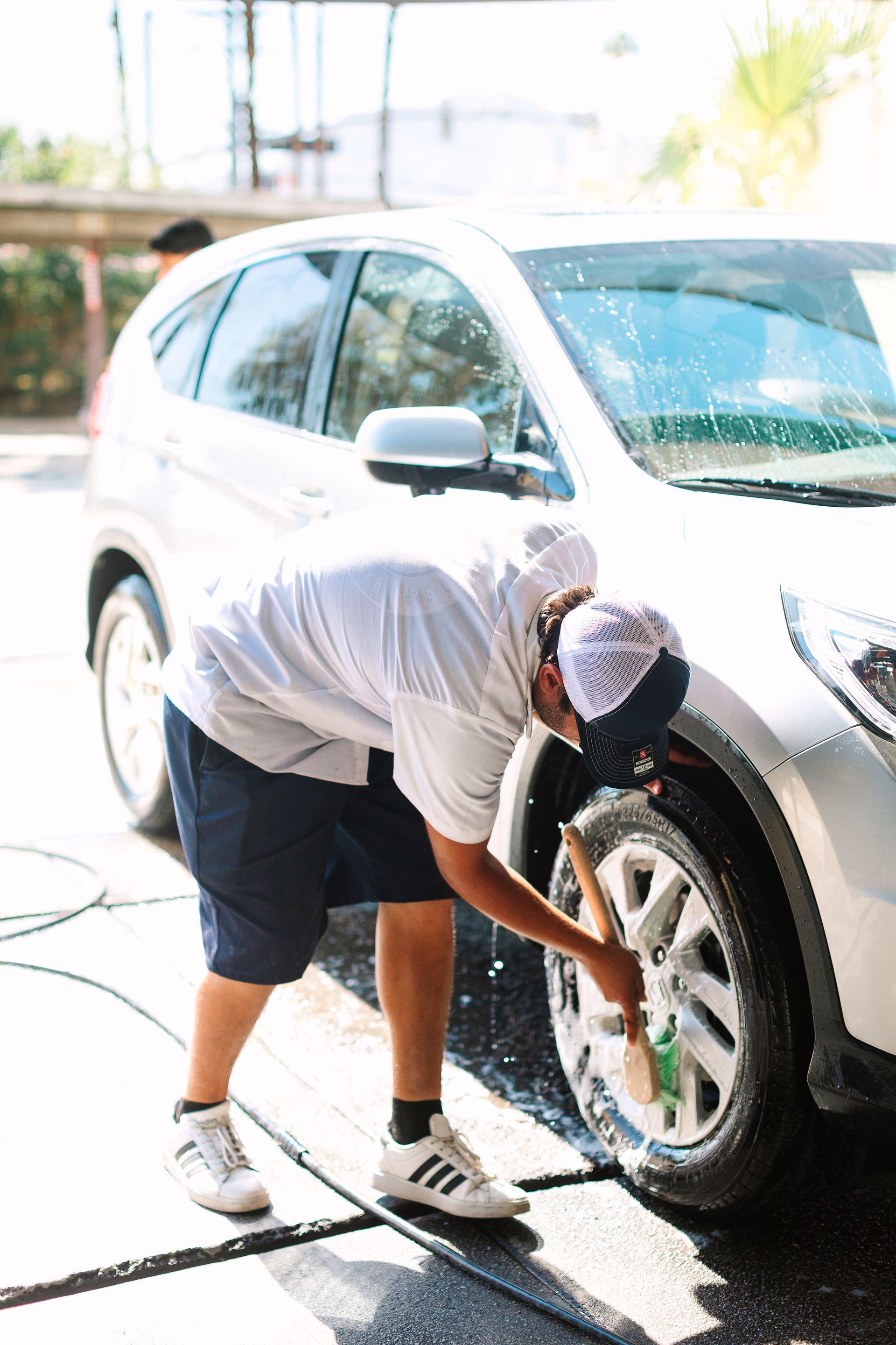 A man is washing a car with a hose.