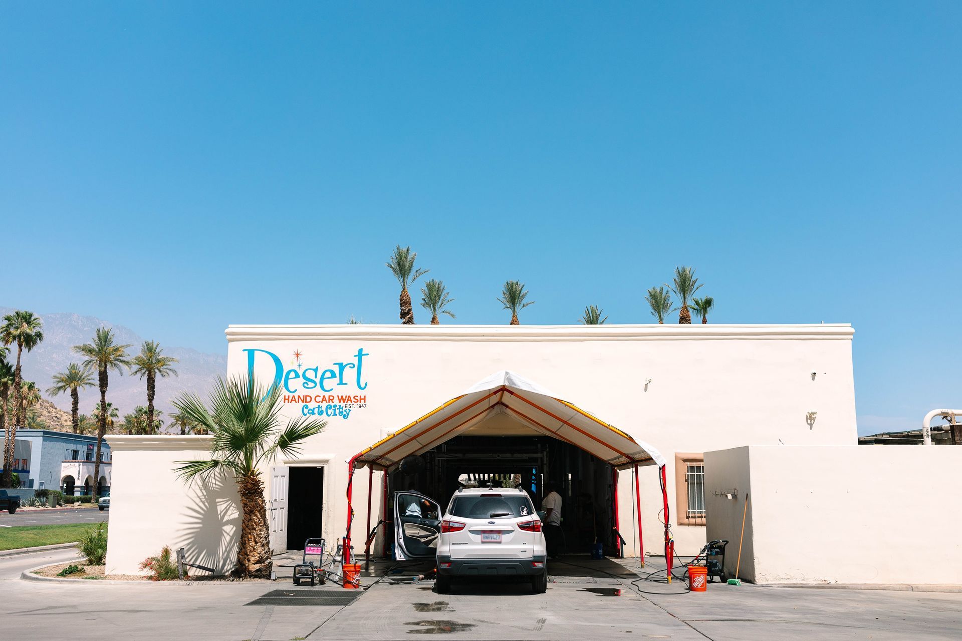 A car is parked in front of a desert car wash.