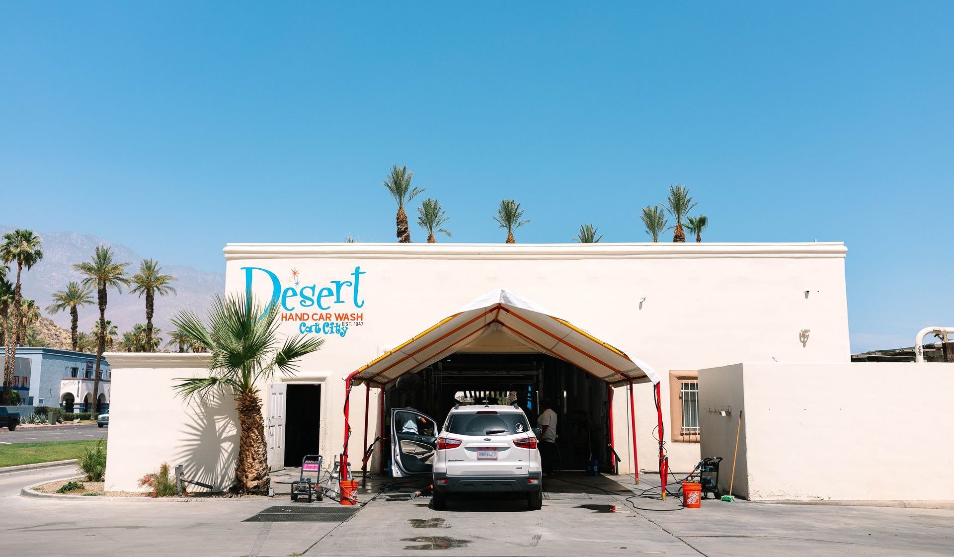 A car is parked in front of a desert springs car wash.