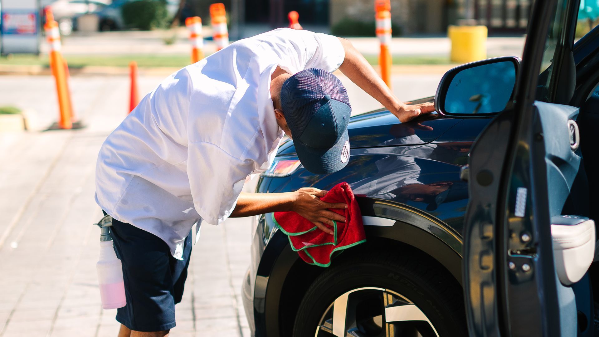 A man is cleaning a car with a towel.