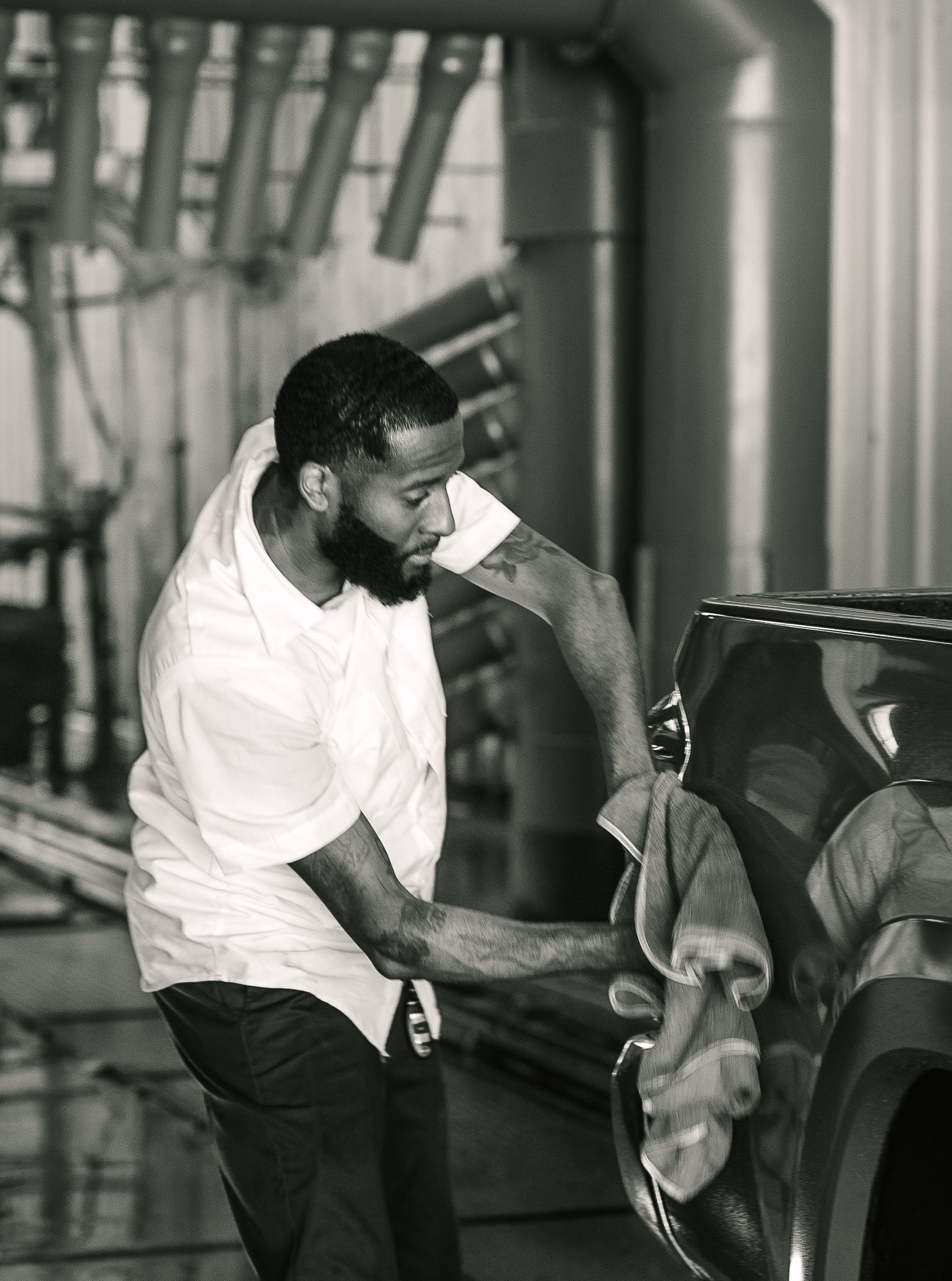 A man is washing a car with a towel in a black and white photo.