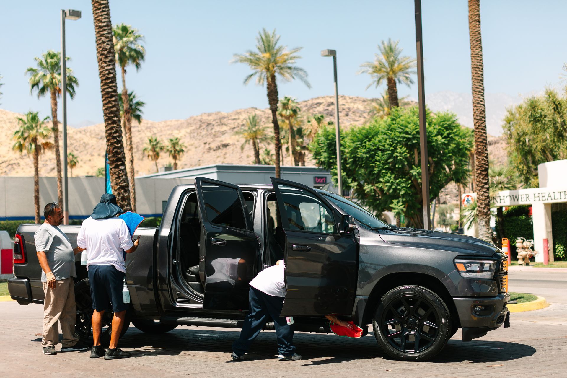 A group of men are standing around a pickup truck with the doors open.