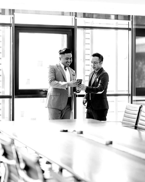 Two men in suits are shaking hands in a conference room.
