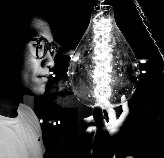 A man with glasses is holding a light bulb in his hand