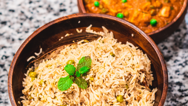 Two bowls of rice and curry are on a table.
