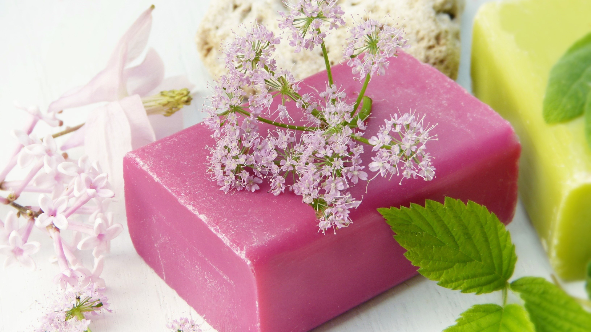 A pink soap bar with flowers on top of it.