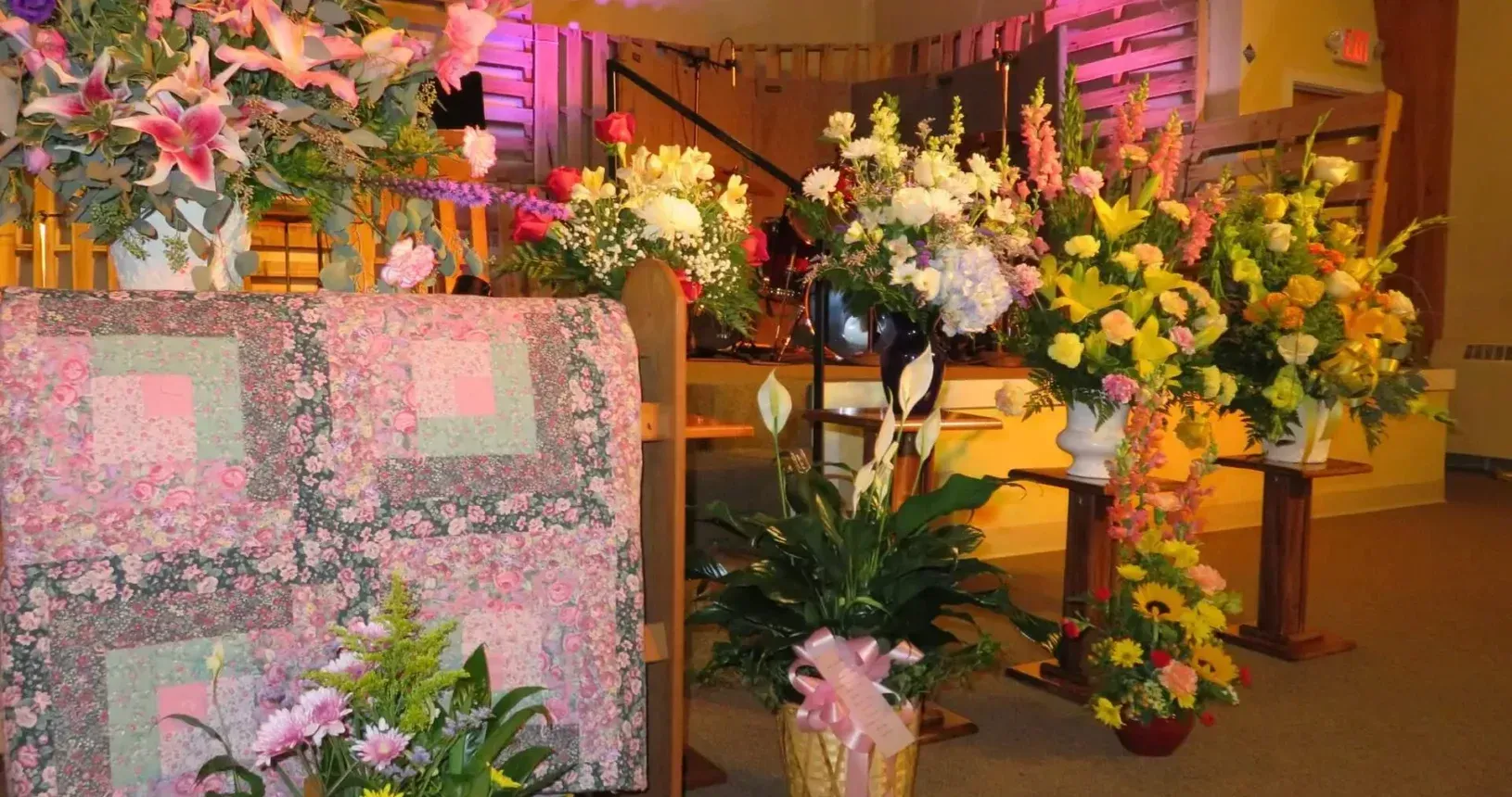 Flower arrangements displayed on pedestals and tables at a warmly lit indoor event venue