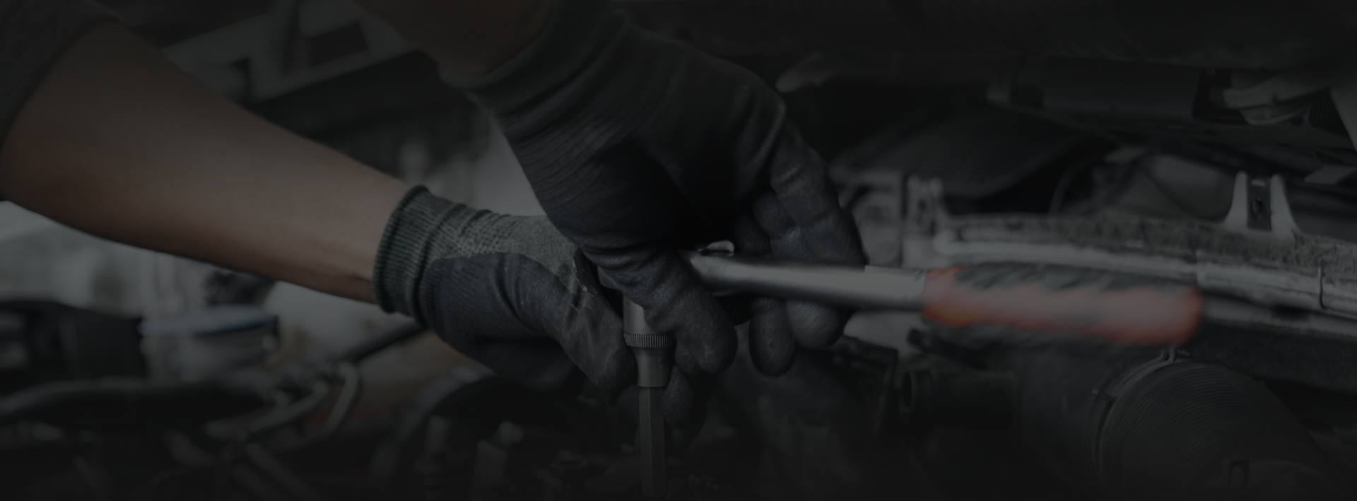 Mechanic's gloved hands using a wrench in an engine bay. | ECP Auto Service