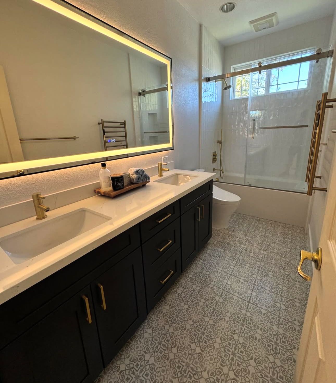 A bathroom with black cabinets and a large mirror