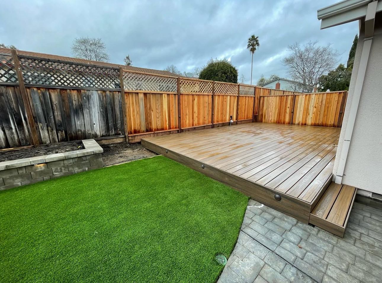 A backyard with a wooden deck and a wooden fence