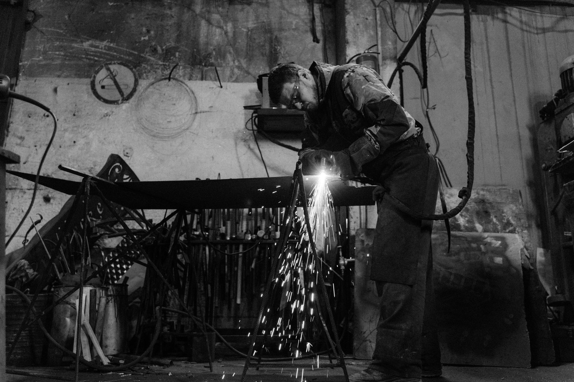 A black and white photo of a man welding a piece of metal