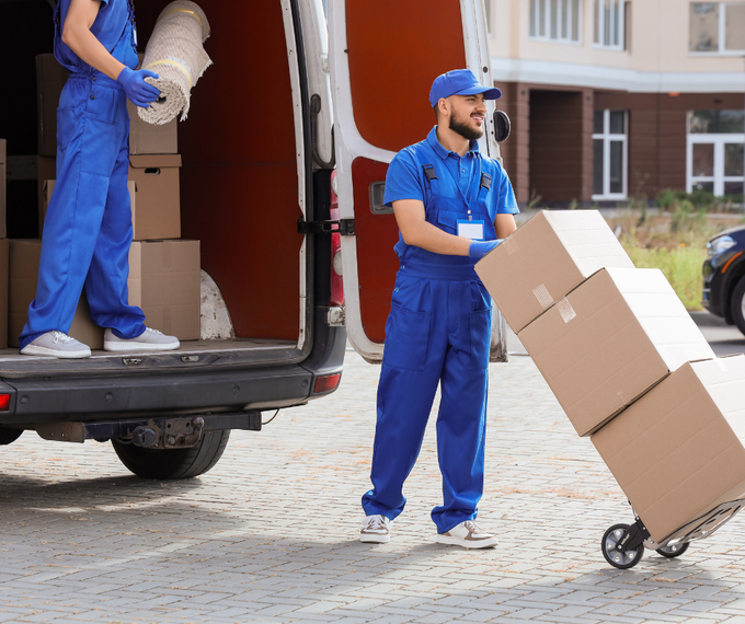 A man and a woman are standing next to a stack of cardboard boxes