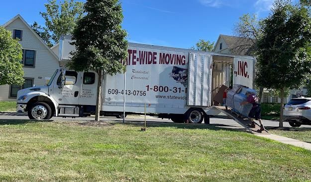 Waste hauler truck with driver collecting compostable yard waste in lawn and leaf bags from a residential area.