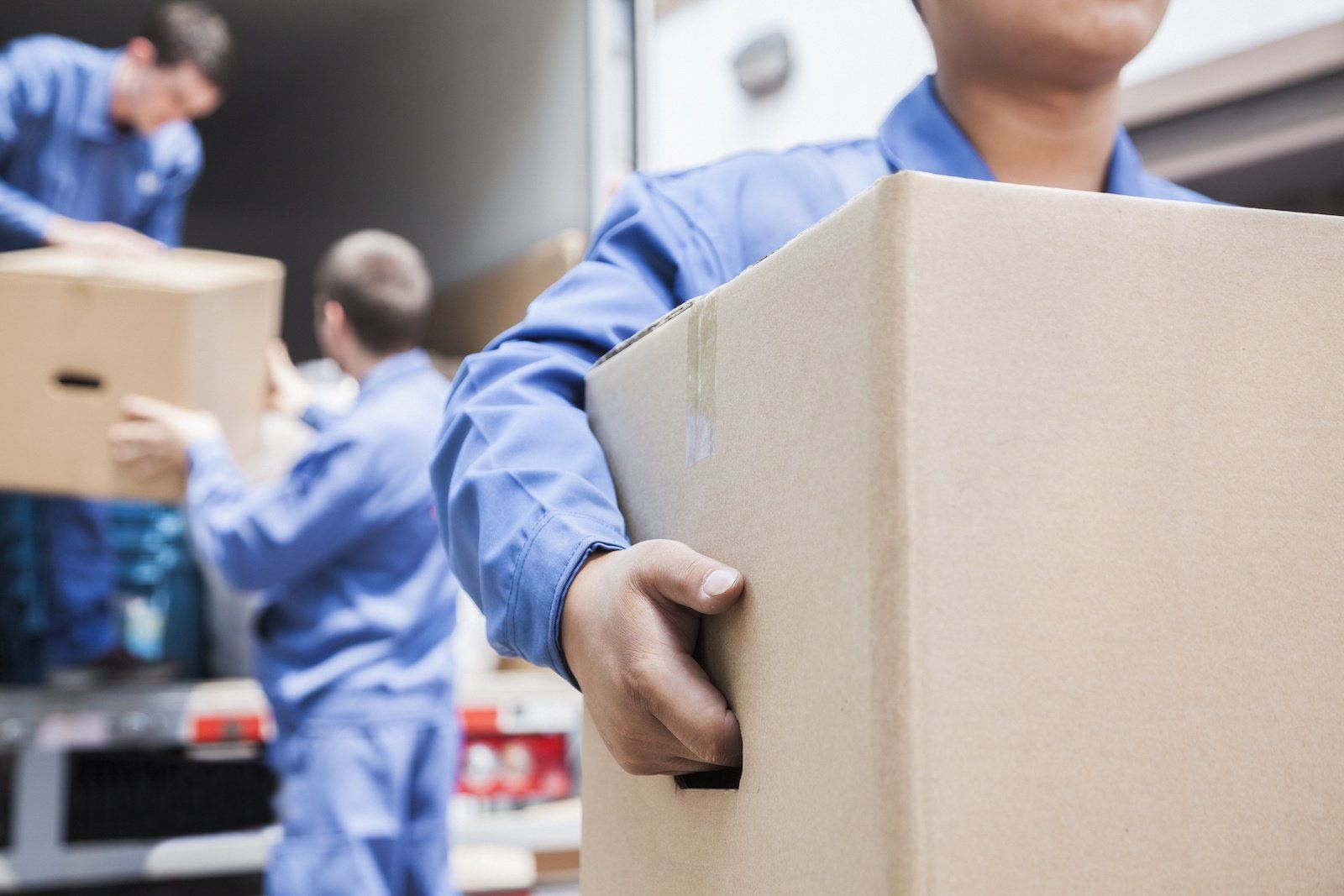 Movers carefully unloading a moving van, carrying boxes and furniture to a new location.